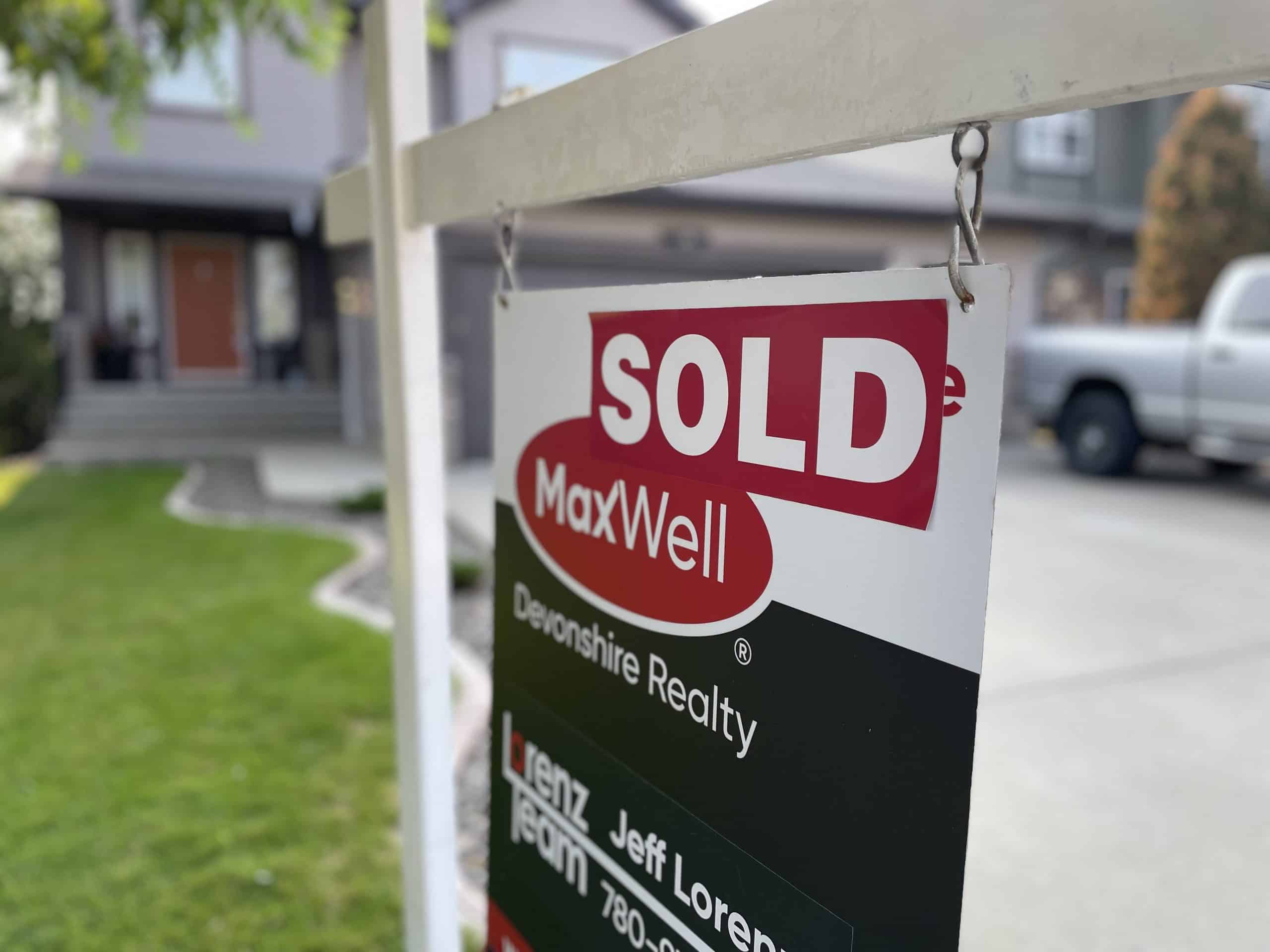 Sold Sign on a lawn with a grey house in the background